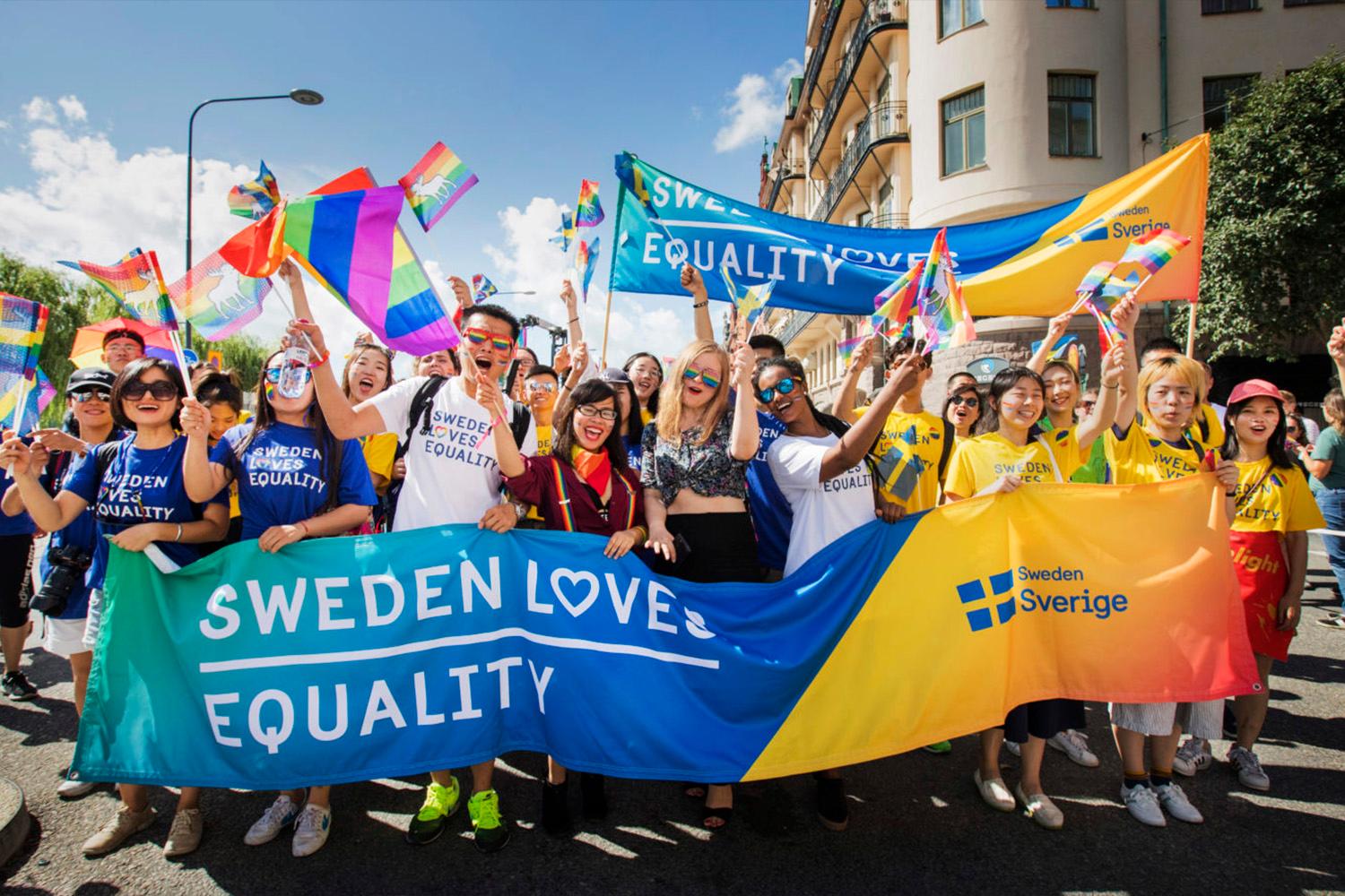 People at a pride parade with a Sweden banner.