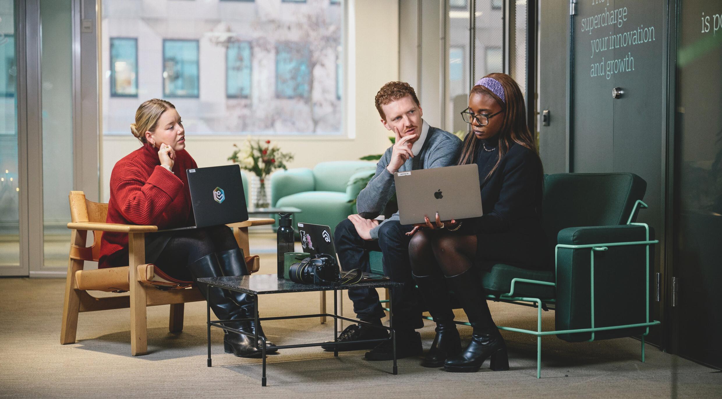 A modern office environment where employees work on laptops.