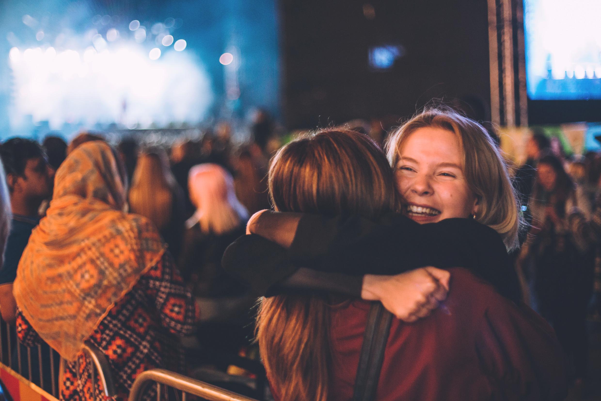 Two friends hugging at a music festival.
