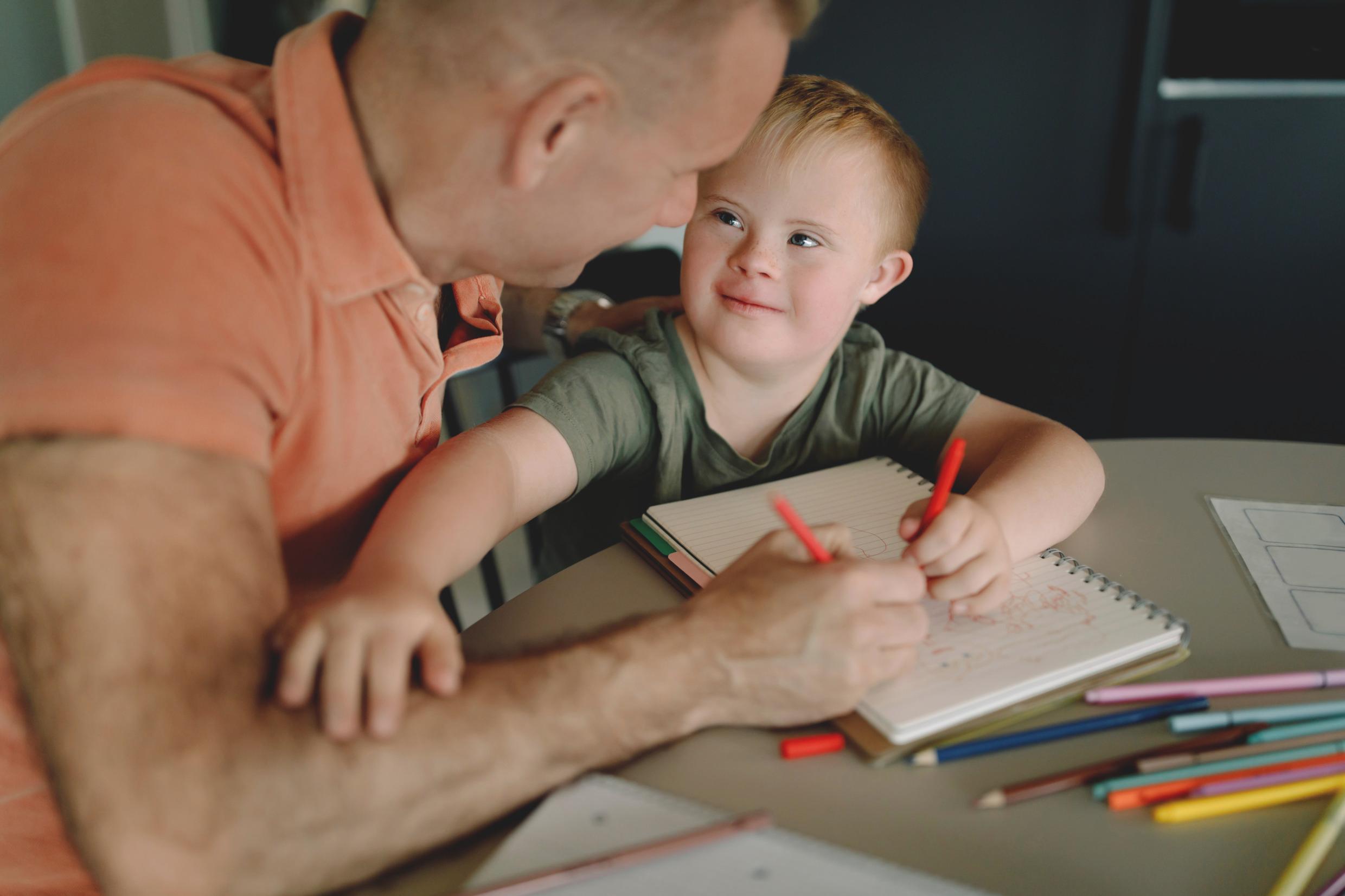 A father and young child making a drawing together.