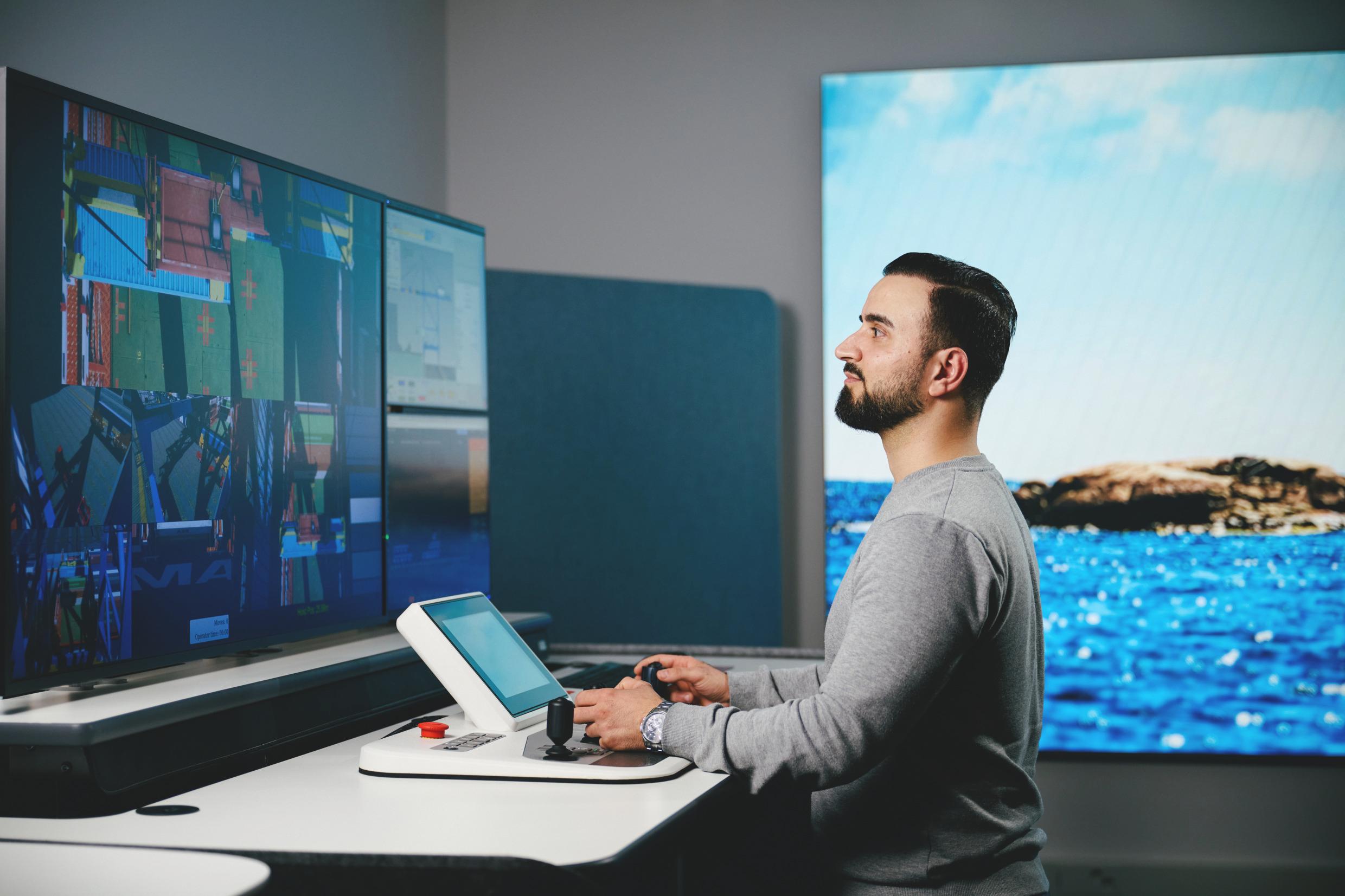 A man sits at a desk looking at a large monitor.