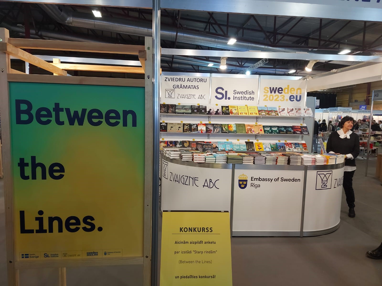 Between the lines-poster and a booth full of books,.