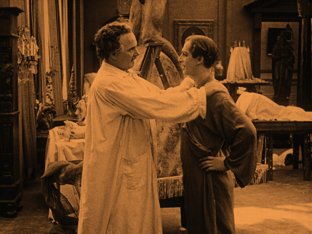 A still from a black and white film of a man touching another mans shoulders.