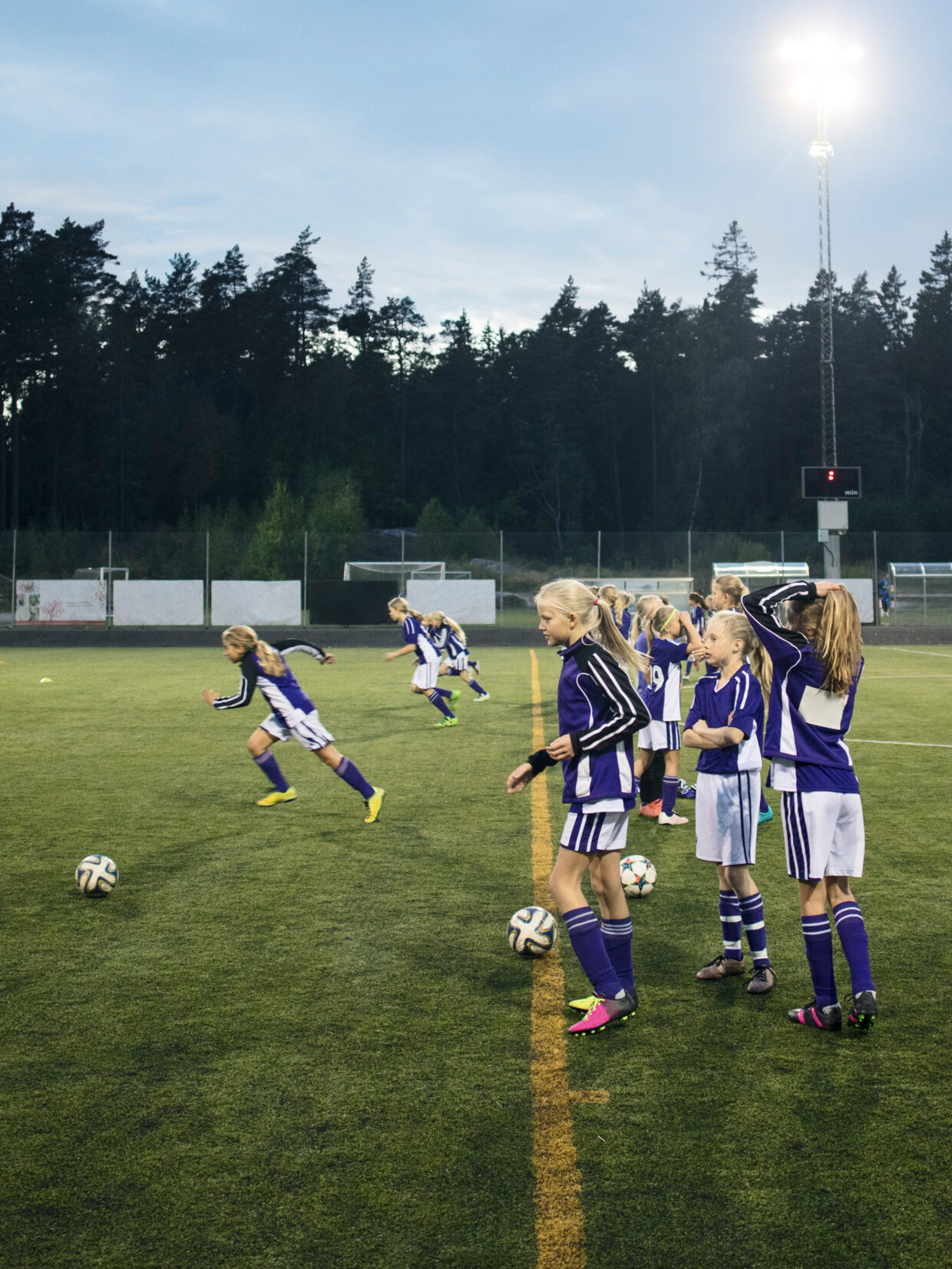 Football pitch with girls practicing in the evening.